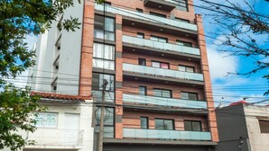 A multi-story residential building with balconies, a garage, and a car parked in front.