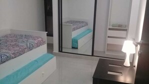 A bedroom with a bed, a mirror, a nightstand, and a lamp.