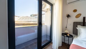A hotel room with a sliding glass door to a balcony, a small bedside table with a lamp, and a bed with a striped headboard.