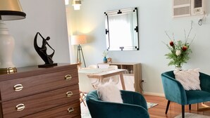 Una sala de estar moderna con un aparador de madera, sillones color turquesa, una mesita redonda y un espejo en la pared.
