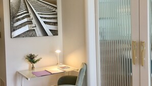 Una habitación con escritorio, silla y una puerta con persianas verticales.