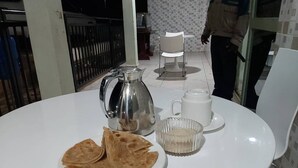 Una mesa redonda blanca con una jarrón, un tazón de azúcar y un plato de pan plano.