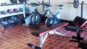 Un gimnasio con equipo de ejercicio, una banca y un estante con mancuernas.