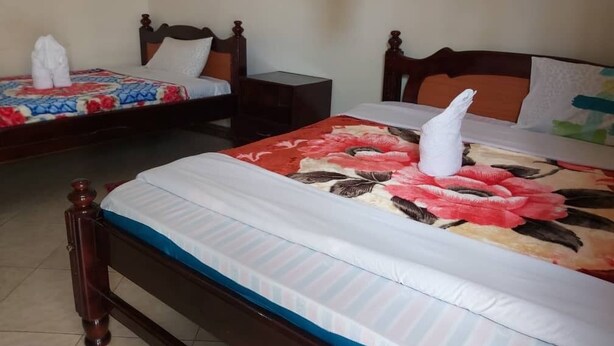 Una habitación de hotel con dos camas, cada una con una colcha estampada con motivos florales y una toalla blanca.