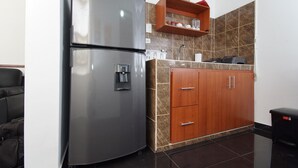 Eine kompakte Küche mit Edelstahlkühlschrank, Holzschränken und einer Marmor-Spritzschutzwand.
