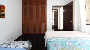 Ein Schlafzimmer mit Bett, Kleiderschrank und einer Tür zu einem anderen Raum.