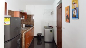 Eine kleine Küche mit Kühlschrank, Spüle und einer Waschmaschine.
