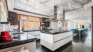 A modern kitchen with a central island, stainless steel appliances, and a dining area with blue chairs. - Aruba luxury villa La Casa Piu Bella your home away from home (Noord)