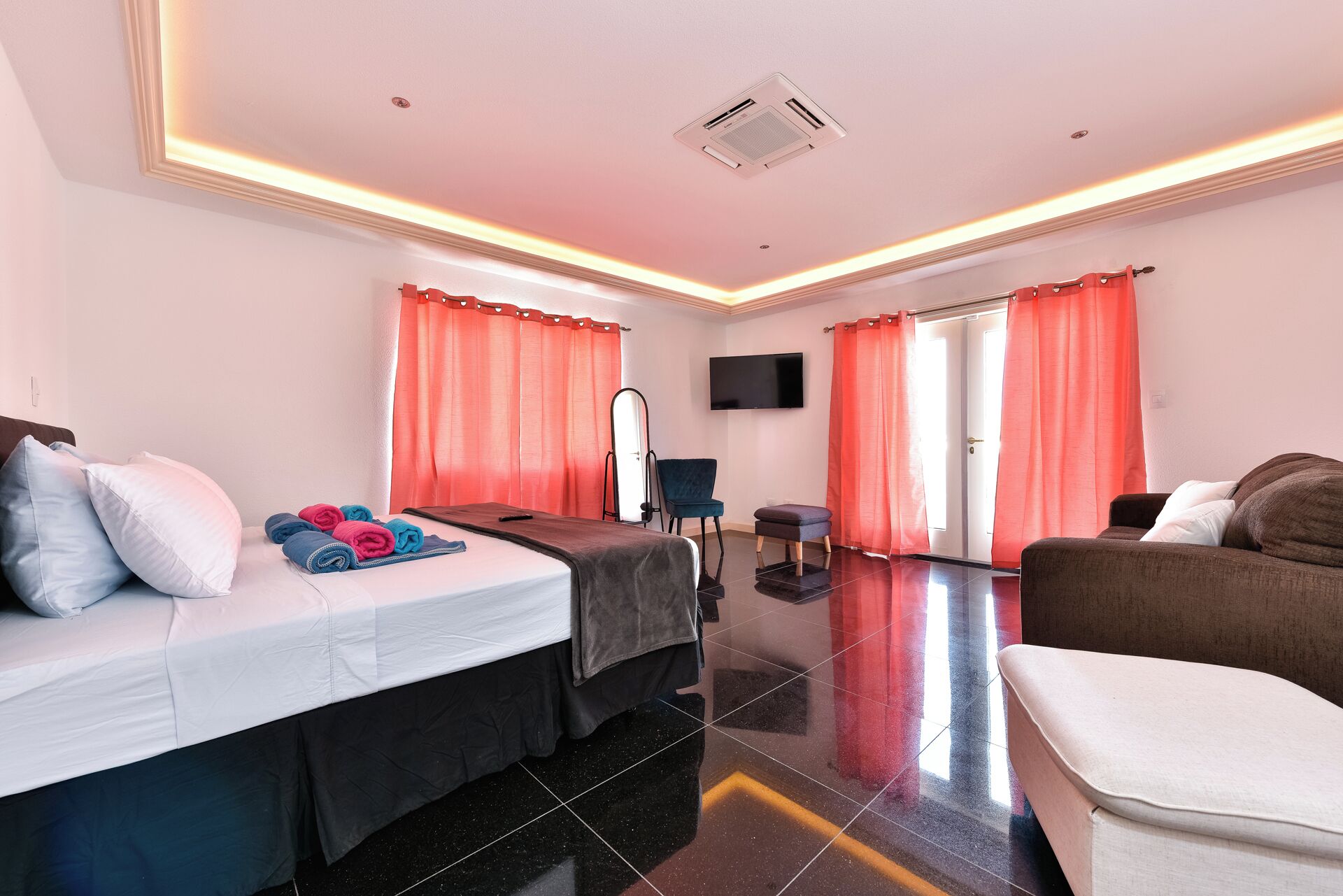 Ein Hotelzimmer mit Bett, Sofa, Fernseher und Spiegel.