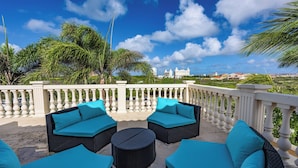A rooftop terrace with wicker furniture and a view of a cityscape. - Aruba luxury villa La Casa Piu Bella your home away from home (Noord)