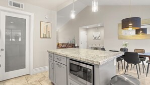A modern kitchen with a granite countertop, stainless steel appliances, and pendant lighting. - The Dava | Free Heated Pool & Putting Green (Tempe)