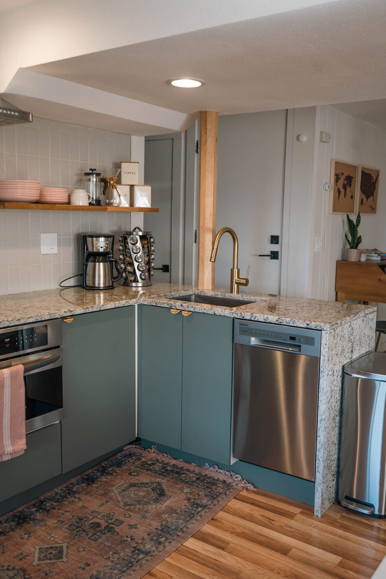 A compact kitchen with a built-in dishwasher, a coffee maker, and a sink with a gold faucet.