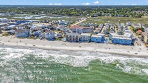Eine Wohngegend an der Küste mit Häusern direkt am Strand, einem Sandstrand und Wellen.