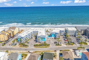 Un hôtel situé sur la côte, composé de plusieurs bâtiments, doté d’un parking et offrant une vue sur la plage.