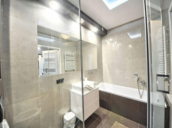 A modern bathroom with a glass-enclosed shower, a freestanding bathtub, and a vanity with a mirror.