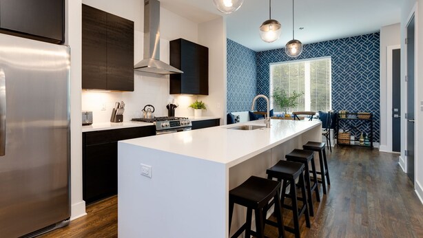 A modern kitchen with a central island, stainless steel appliances, pendant lighting, and a patterned backsplash. - SKYLINE ROOFTOP DECK 4 BEDROOMS KING BED LARGE KITCHEN L2 EV CHARGER PETS GARAGE (Nashville)