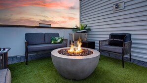 A rooftop patio with a fire pit, two sofas, and a potted plant. - SKYLINE ROOFTOP DECK 4 BEDROOMS KING BED LARGE KITCHEN L2 EV CHARGER PETS GARAGE (Nashville)