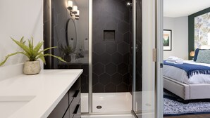 A modern bathroom with a glass shower enclosure, a white sink, and a potted plant. - SKYLINE ROOFTOP DECK 4 BEDROOMS KING BED LARGE KITCHEN L2 EV CHARGER PETS GARAGE (Nashville)