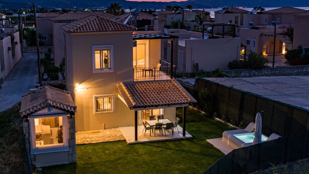 Une maison à deux étages dotée d’un patio, d’une piscine et offrant une vue sur le quartier environnant au crépuscule.