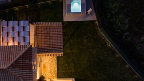 Vue aérienne d’un quartier résidentiel avec une piscine, un espace de détente extérieur et un mur en pierre.
