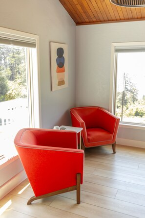 A room with two red chairs, a white table, and a painting on the wall.