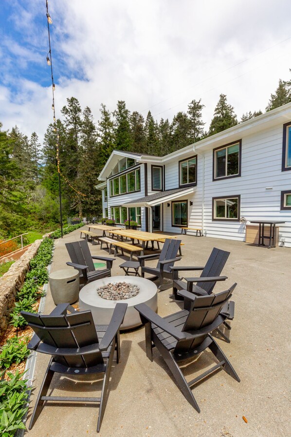 An outdoor patio with Adirondack chairs, a fire pit, and a dining table.