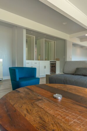 Una sala de estar moderna con una mesa de centro redonda de madera, un sillón azul y un sofá gris.