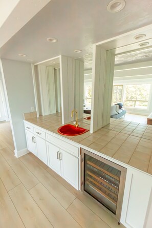 A modern kitchen with a red sink, white cabinets, and a built-in oven. - Mervue Estate - Luxury ocean view on 60 acres (Gold Beach)