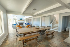 A spacious dining area with a long wooden table, benches, and modern chairs.