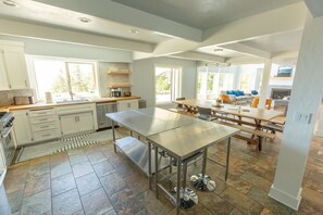 Una cocina amplia con una isla grande, mucho espacio en las encimeras y un comedor con varias mesas.