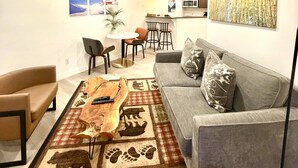 A living room with a gray sofa, a coffee table, and a rug with animal prints. - Heart of the Village. Newly renovated , modern décor throughout, Central AC just installed 2024 (Whistler)