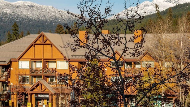 A wooden building with a balcony, a liquor store, and a view of snow-capped mountains. - Heart of the Village. Newly renovated , modern décor throughout, Central AC just installed 2024 (Whistler)