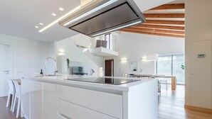 Eine moderne Küche mit einer zentralen Kochinsel, integrierten Geräten und einer Treppe, die zu einer oberen Ebene führt.