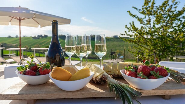 Ein Tisch mit einer Flasche, Gläsern und Schalen mit Obst.