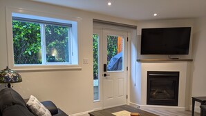 Un salon comprenant un canapé, une table basse, une cheminée et un téléviseur fixé au mur.