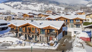 A snow-covered village with wooden houses, a clear sky, and mountains in the background. - Stylish penthouse with shared sauna and lift (Walchen)
