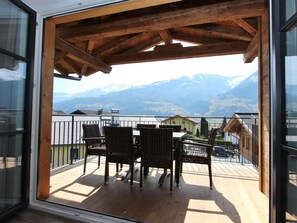 A wooden deck with wicker chairs and a table, overlooking a mountain landscape. - Stylish penthouse with shared sauna and lift (Walchen)
