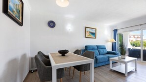 Uma sala de estar moderna com uma mesa de jantar, cadeiras, um sofá e uma mesa de centro.