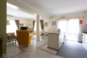 Una habitación de hotel con sala de estar, comedor, cocina y zona de lavandería.