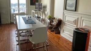 Un espace repas comprenant une longue table, des chaises, un téléviseur et des œuvres d’art encadrées accrochées au mur.