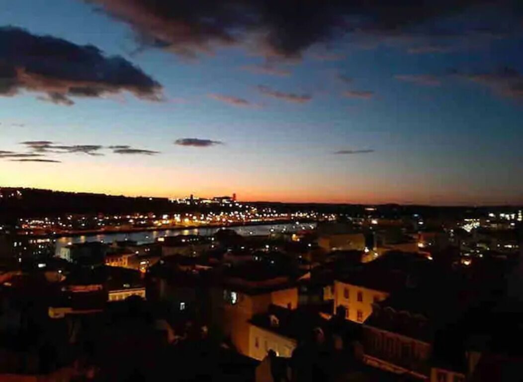 Une vue nocturne d'une ville, avec une rivière et des bâtiments illuminés.
