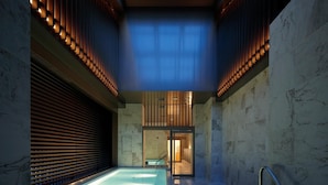 Un área de spa con una piscina grande, paredes de listones de madera y vistas del espacio interior.