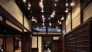 Un interior japonés tradicional con suelo de tatami, vigas de madera y lámparas de vidrio colgantes.