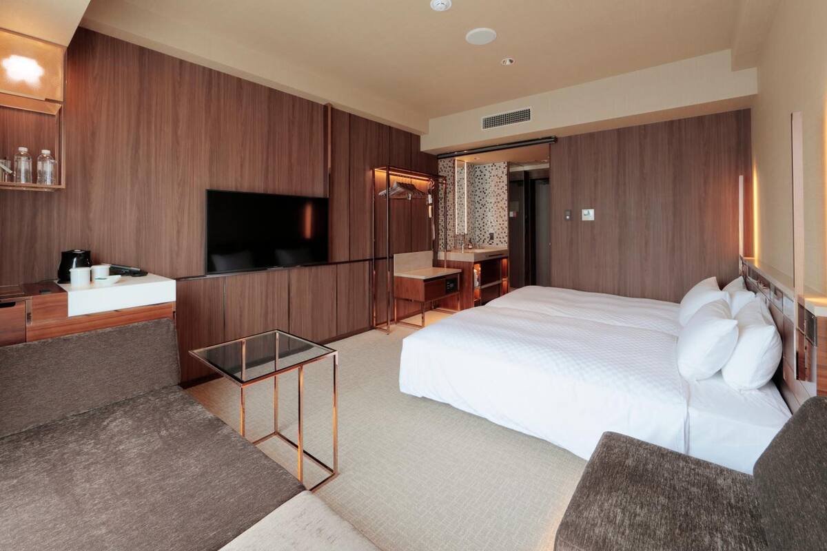 Una habitación de hotel moderna con una cama grande, televisión, escritorio y zona de estar.