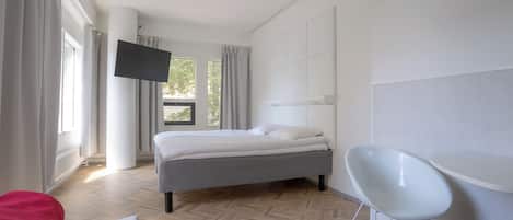 A modern bedroom with a bed, a TV mounted on the wall, and a chair.