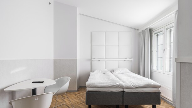 A modern, minimalist bedroom with a bed, a small table, and a chair. - Omena Hotel Turku Kauppiaskatu (Turku)
