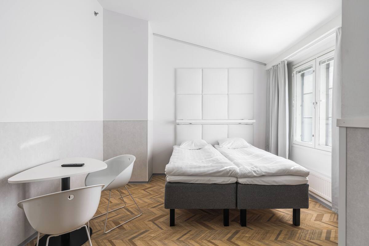 A modern, minimalist bedroom with a bed, a small table, and a chair.