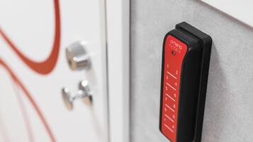A red keycard with "omena hotels" and a keypad on a metallic surface.