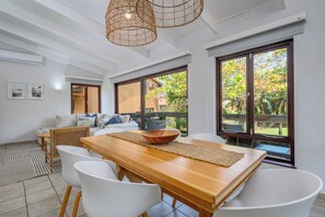 A dining area with a wooden table, white chairs, and a woven bowl centerpiece. - San Lameer Villa Rentals 2907 (Southbroom)
