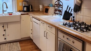 Une cuisine compacte avec des meubles blancs, un four à micro-ondes, une cuisinière et une machine à café.